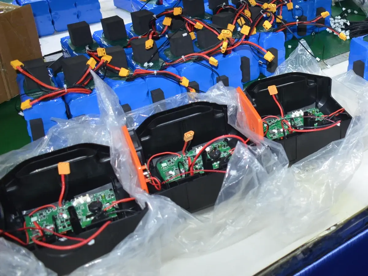 Multiple open portable power station housings with circuit boards and wiring assemblies on a partner production workbench